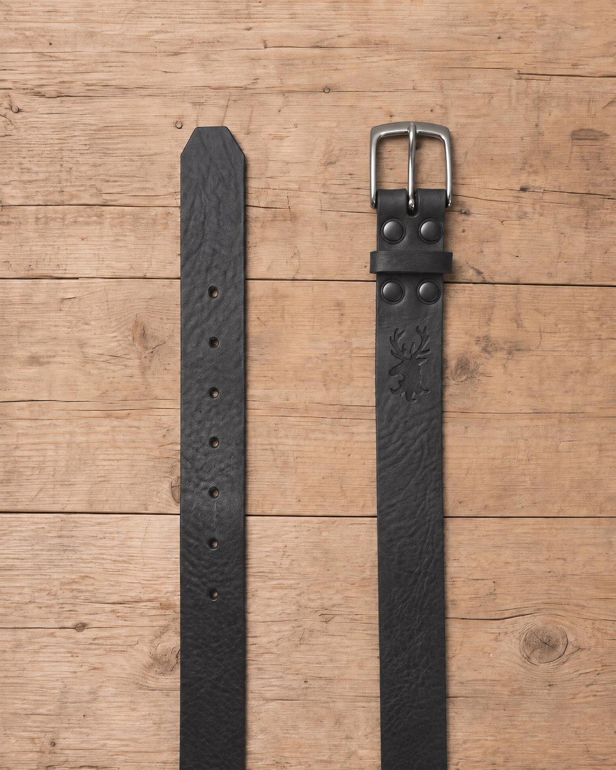 slim suit belt made of full grain vegetal leather in black colour with polished brass style metal buckle on a rustic wooden table